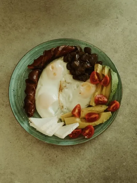 Eggs, sausage, avocado and feta on a green plate