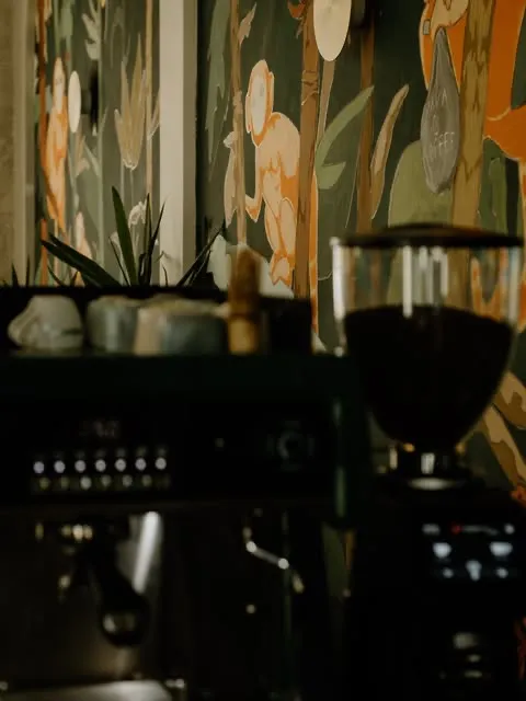 Behind the bar — the espresso machine and grinder against the painted jungle mural