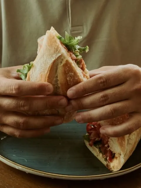 A baguette sandwich held over a blue plate