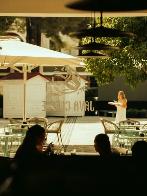 The Centrale terrace at golden hour — umbrellas, the Java Coffee kiosk and its monkey sign